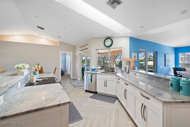 kitchen featuring light parquet flooring, dishwasher, white cabinetry, vaulted ceiling with skylight, and light stone counters