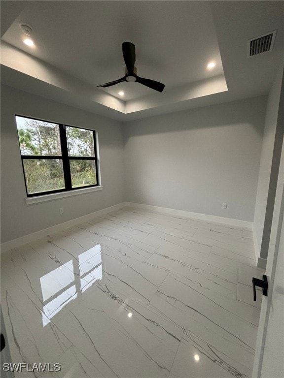 spare room featuring a raised ceiling and ceiling fan