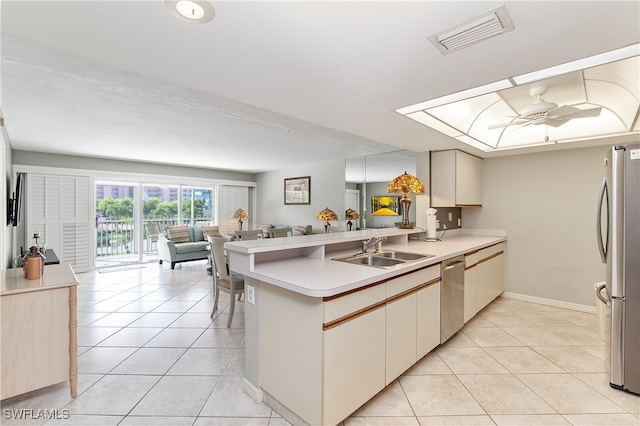 kitchen with light tile patterned floors, sink, appliances with stainless steel finishes, and kitchen peninsula