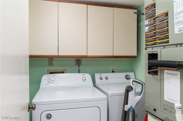 clothes washing area featuring cabinets, heating unit, and washing machine and clothes dryer