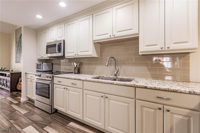 kitchen featuring decorative backsplash, stainless steel appliances, sink, dark hardwood / wood-style floors, and white cabinetry