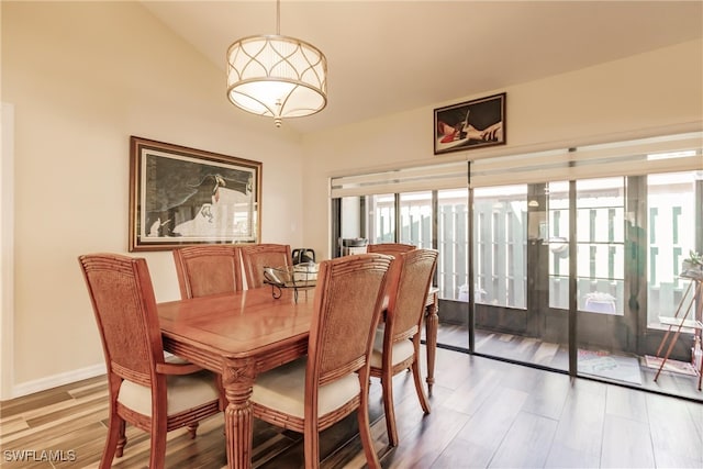 dining room with plenty of natural light, wood-type flooring, and lofted ceiling