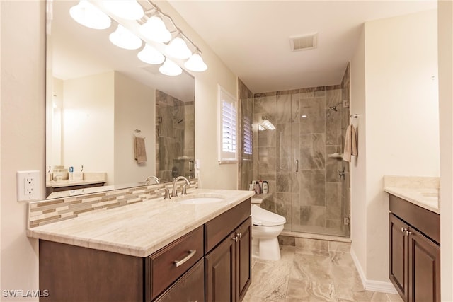 bathroom with vanity, toilet, a shower with door, and backsplash