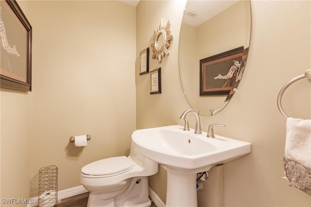 bathroom featuring wood-type flooring, toilet, and sink