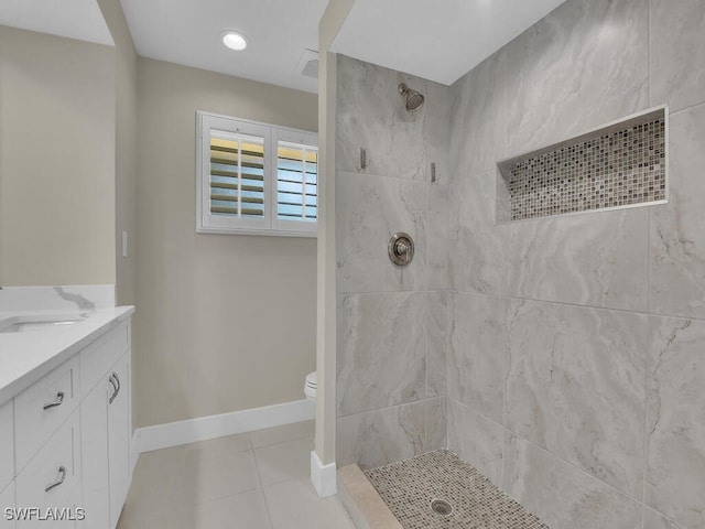 bathroom with tiled shower, vanity, toilet, and tile patterned floors