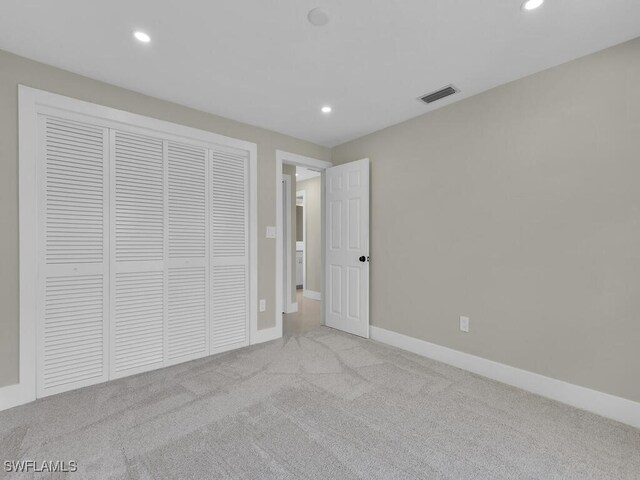 unfurnished bedroom with light carpet and a closet