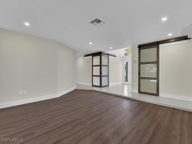 empty room featuring a barn door and dark hardwood / wood-style floors