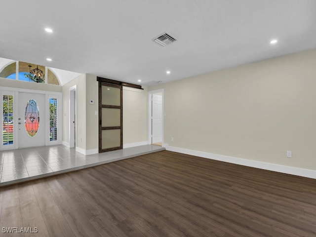 interior space with a barn door and dark hardwood / wood-style flooring