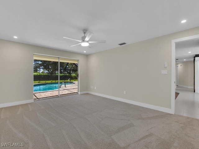 carpeted spare room with a barn door and ceiling fan