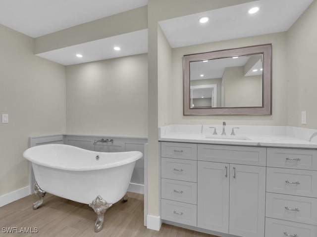 bathroom with wood-type flooring, a bath, and vanity