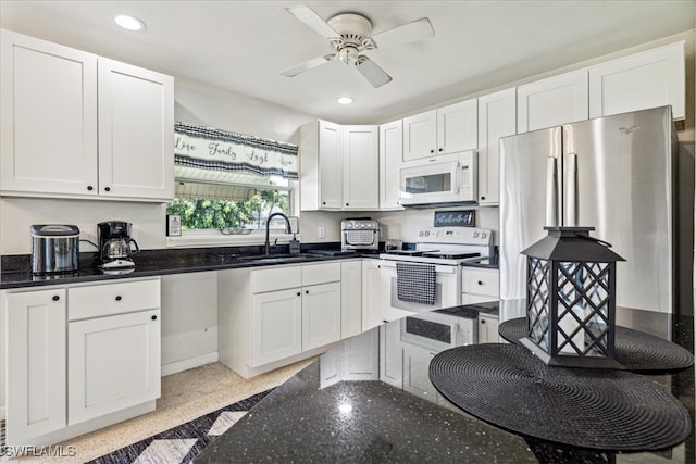 kitchen featuring sink, white cabinets, white appliances, dark stone countertops, and ceiling fan