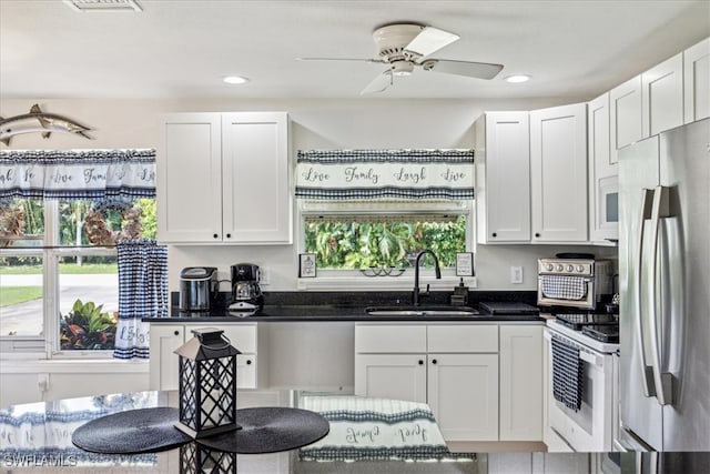 kitchen featuring ceiling fan, white cabinets, stainless steel fridge, sink, and electric stove