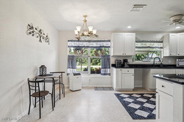 kitchen featuring ceiling fan with notable chandelier, hanging light fixtures, sink, and white cabinetry