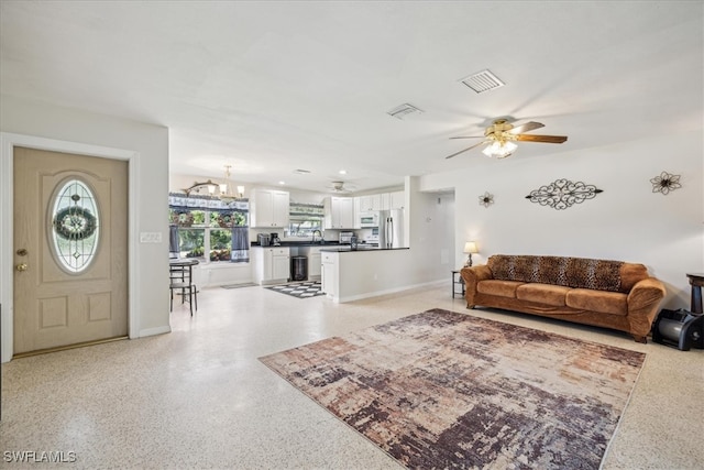 living room featuring ceiling fan with notable chandelier