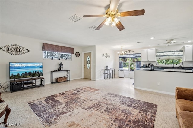 living room with ceiling fan with notable chandelier and sink