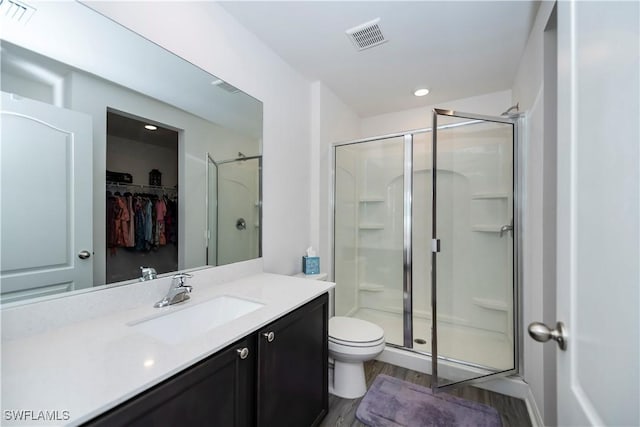 bathroom with hardwood / wood-style floors, vanity, toilet, and an enclosed shower