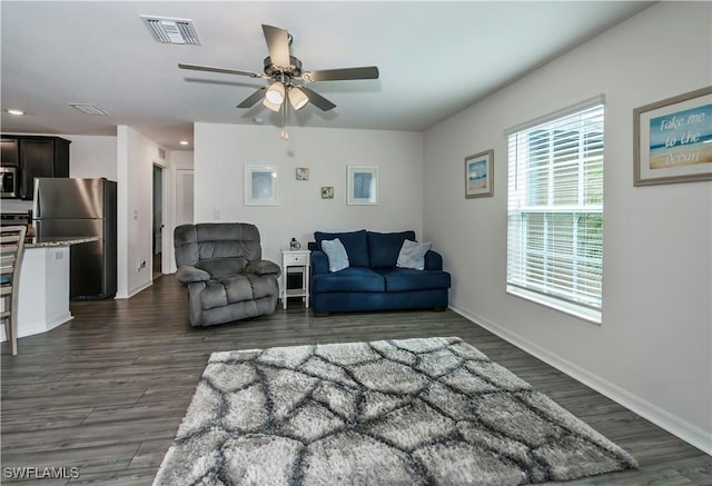 living room featuring ceiling fan and dark wood-type flooring