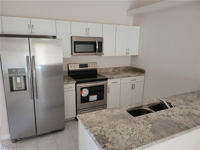 kitchen with appliances with stainless steel finishes, light stone countertops, white cabinetry, and sink