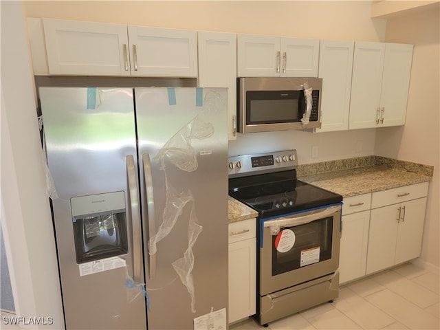 kitchen with light stone counters, white cabinets, and stainless steel appliances