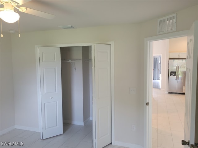 unfurnished bedroom with ceiling fan, a closet, and stainless steel fridge with ice dispenser