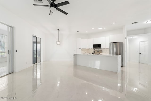 kitchen with ceiling fan, pendant lighting, backsplash, white cabinetry, and stainless steel appliances