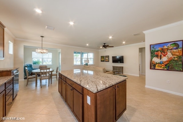 kitchen featuring light stone countertops, decorative light fixtures, ornamental molding, and a center island