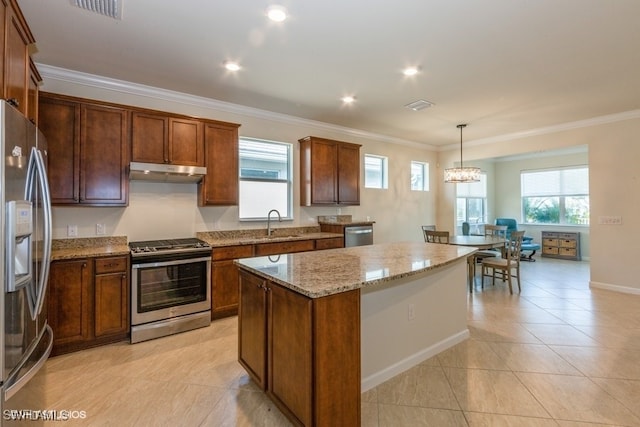 kitchen with light stone counters, pendant lighting, stainless steel appliances, a center island, and crown molding