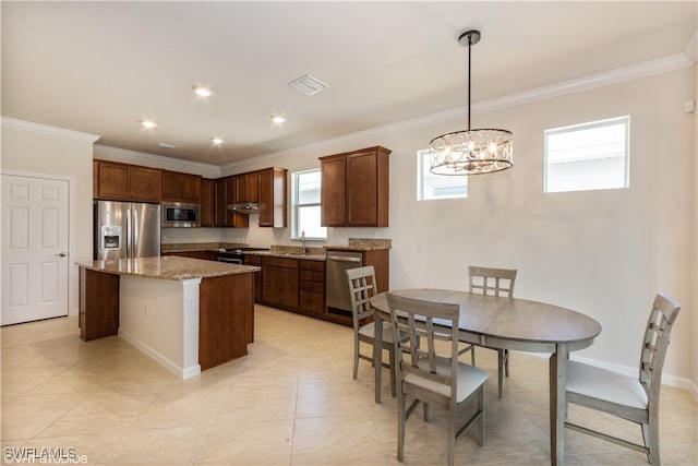 kitchen featuring pendant lighting, a kitchen island, stainless steel appliances, ornamental molding, and light stone countertops