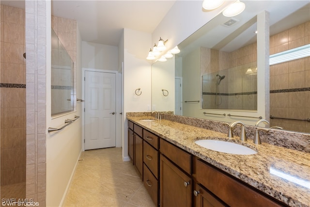 bathroom featuring tile patterned flooring, vanity, and tiled shower