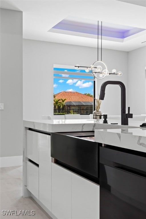 kitchen featuring decorative light fixtures, a raised ceiling, and white cabinets