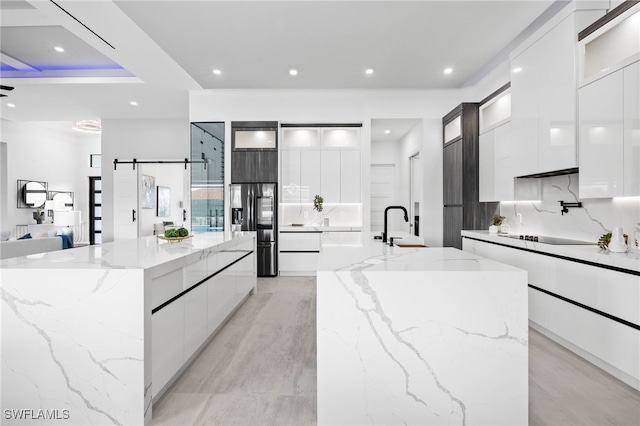 kitchen featuring light stone countertops, a barn door, backsplash, and a spacious island