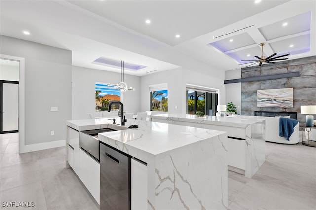 kitchen with light stone countertops, sink, pendant lighting, white cabinetry, and a large island