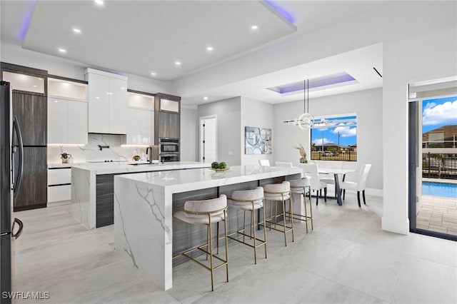 kitchen featuring a kitchen island, white cabinets, sink, decorative light fixtures, and a kitchen breakfast bar