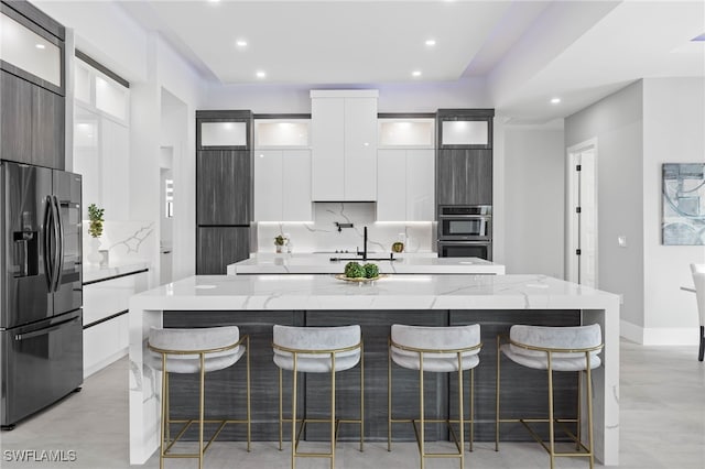 kitchen featuring an island with sink, a breakfast bar area, appliances with stainless steel finishes, and white cabinets