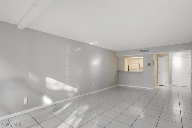 empty room with beam ceiling and light tile patterned floors