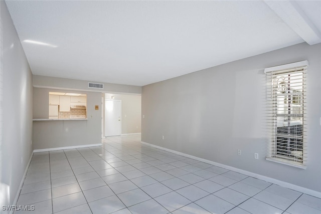 spare room featuring beamed ceiling and light tile patterned floors