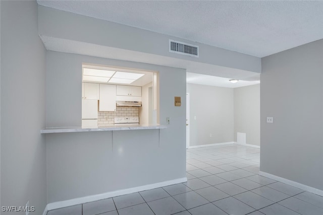 unfurnished room featuring light tile patterned floors and a textured ceiling