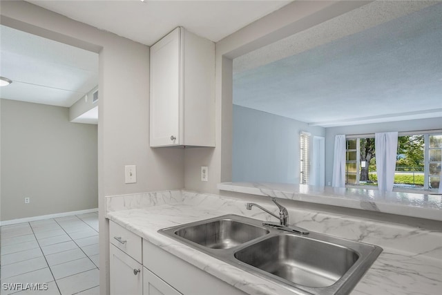 kitchen with sink, light tile patterned floors, and white cabinetry