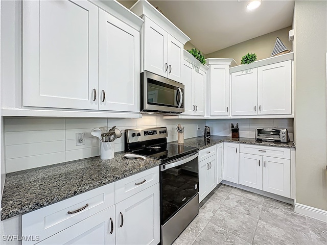 kitchen with decorative backsplash, dark stone countertops, white cabinetry, and stainless steel appliances