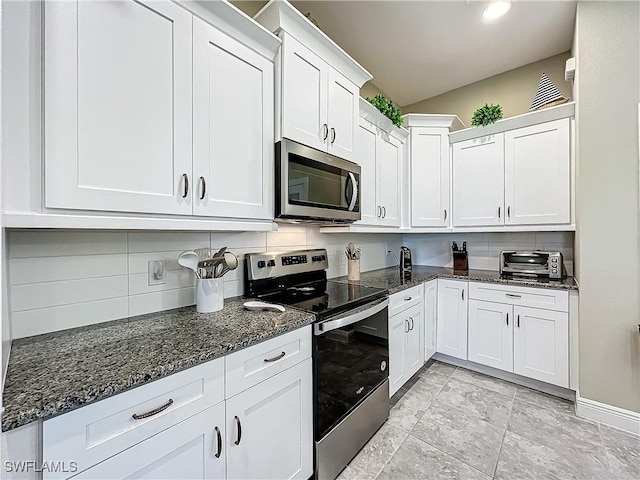 646 NE 5th Place, Cape Coral, FL 33909 - kitchen with appliances with stainless steel finishes, backsplash, white cabinetry, dark stone countertops, and baseboards