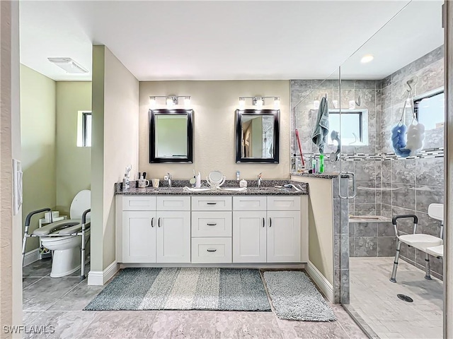 646 NE 5th Place, Cape Coral, FL 33909 - bathroom featuring a shower stall, baseboards, double vanity, and toilet