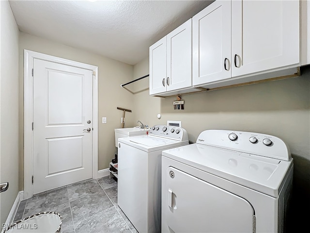 laundry area featuring separate washer and dryer, sink, cabinets, and a textured ceiling