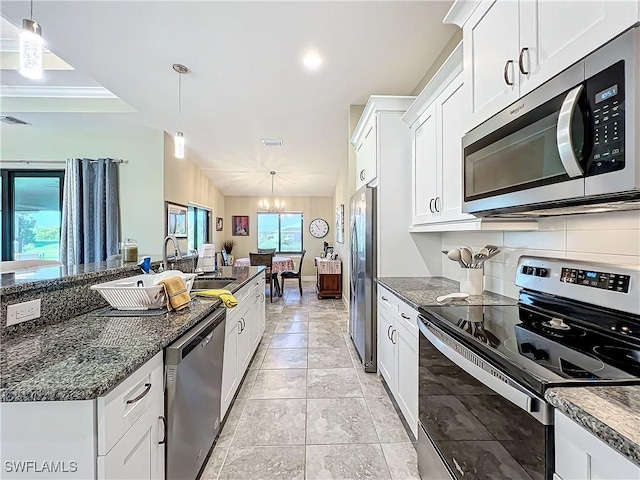 646 NE 5th Place, Cape Coral, FL 33909 - kitchen with appliances with stainless steel finishes, a sink, white cabinetry, decorative backsplash, and a chandelier