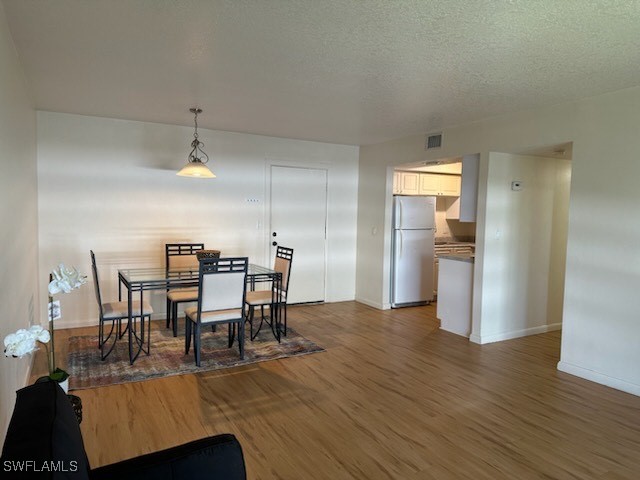 dining area with a textured ceiling and dark hardwood / wood-style floors