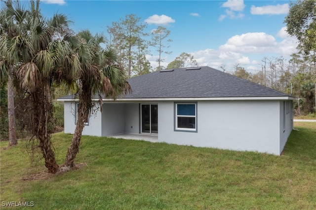 back of property with a yard, a patio, a shingled roof, and stucco siding