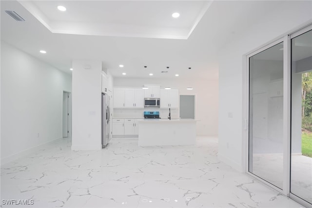 kitchen with light countertops, visible vents, appliances with stainless steel finishes, white cabinetry, and an island with sink