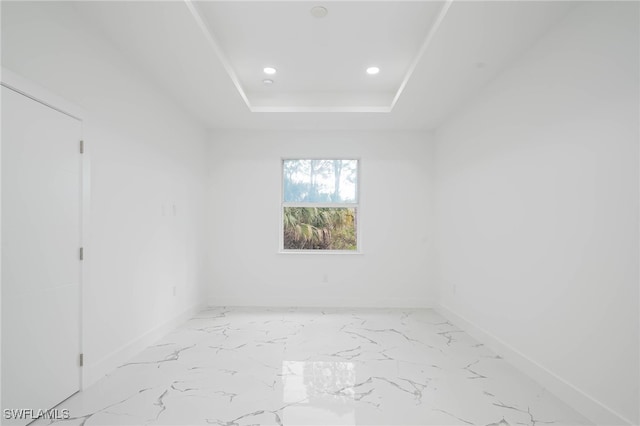 spare room featuring marble finish floor, recessed lighting, a raised ceiling, and baseboards