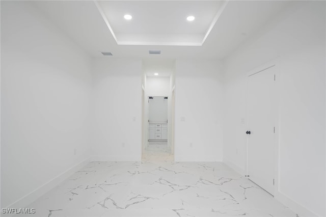 spare room featuring baseboards, visible vents, a raised ceiling, marble finish floor, and recessed lighting