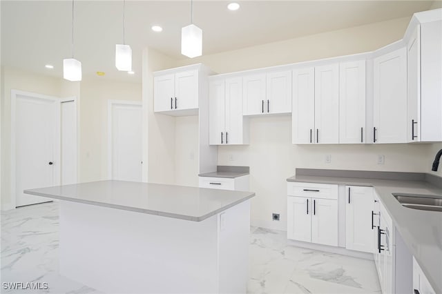 kitchen featuring recessed lighting, marble finish floor, white cabinetry, and a sink