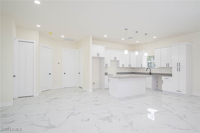 kitchen with recessed lighting, a sink, a kitchen island, white cabinetry, and marble finish floor